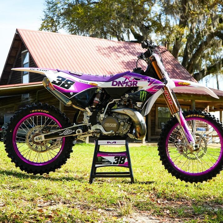 Pink and white two-stroke dirt bike on a stand